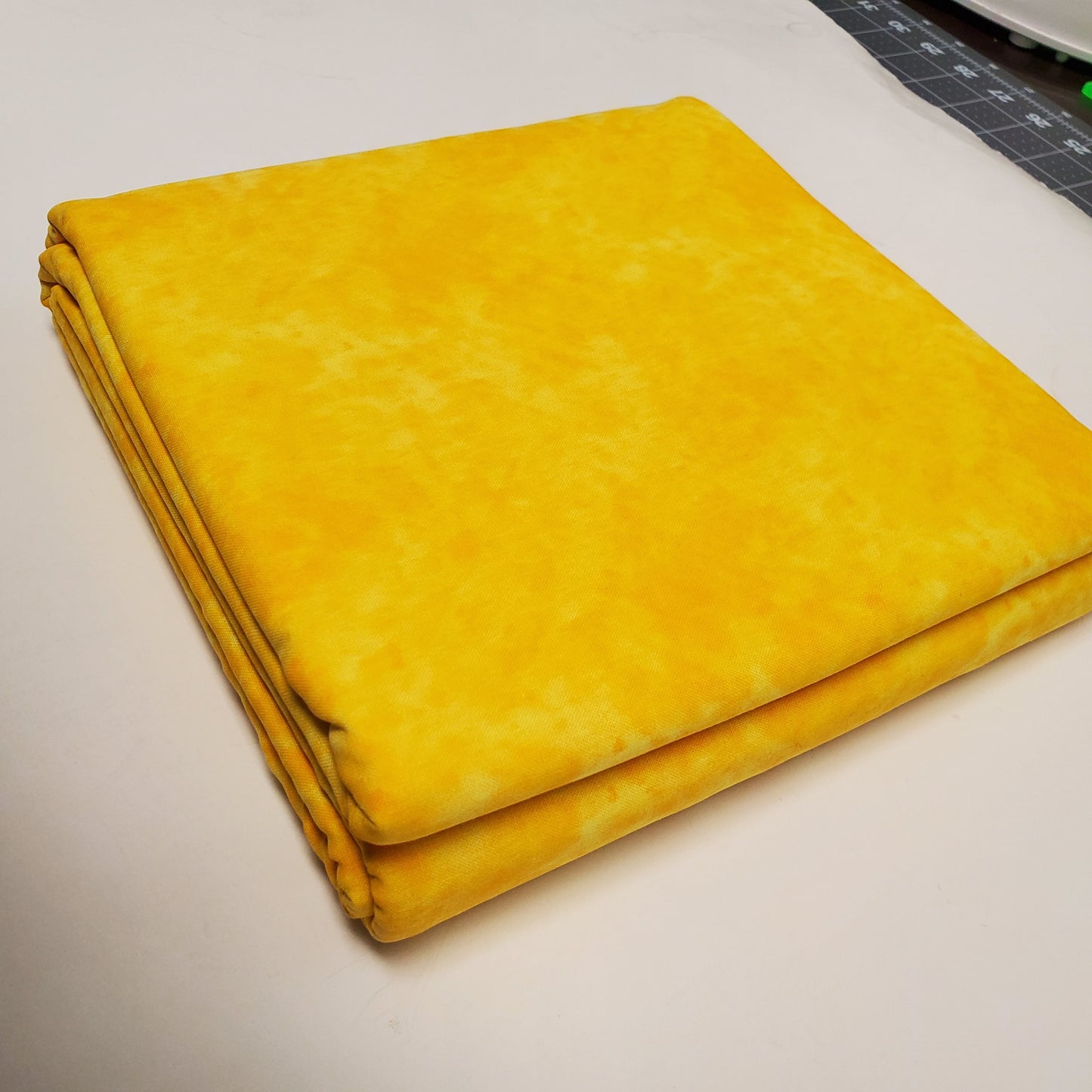 Yellow fabric on a white surface with a ruler in the corner
